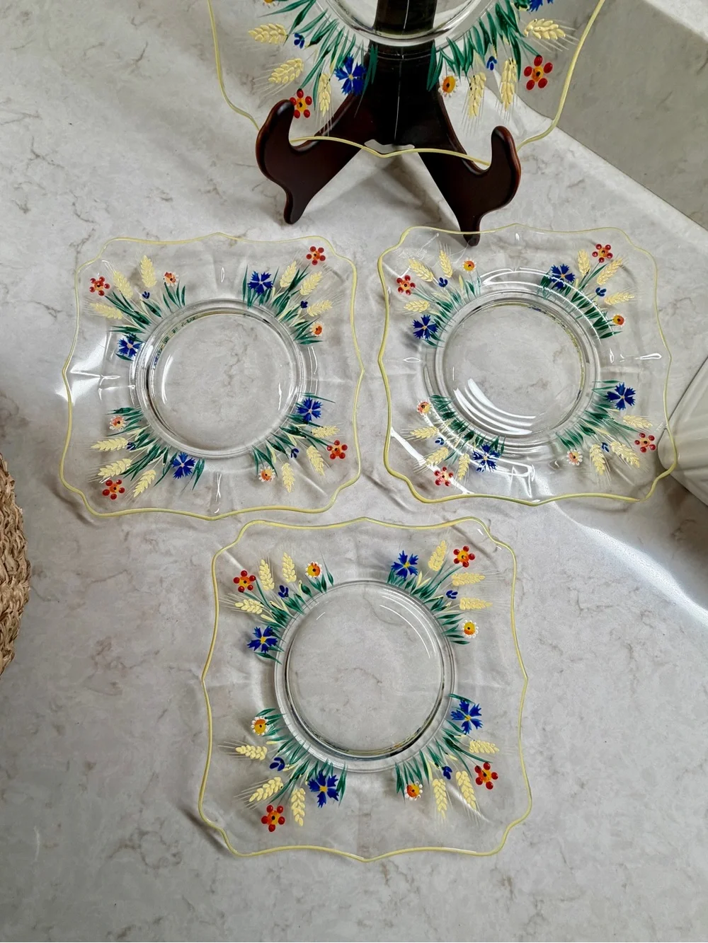 7 1/4” CLEAR GLASS PLATES WITH A COLORFUL, HAND-PAINTED DESIGN & YELLOW TRIM.